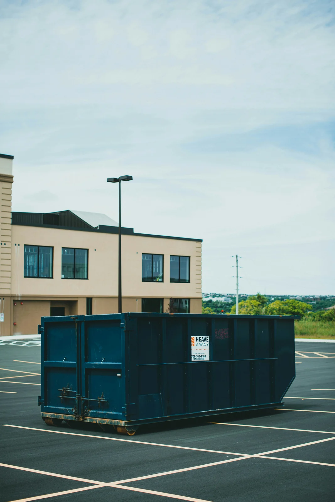 An empty roll-off container standing on an open parking lot